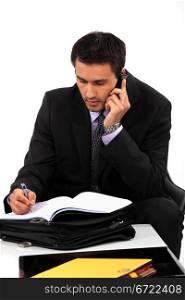 Businessman taking notes during important call