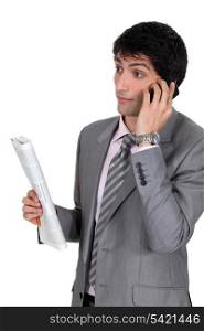Businessman taking on phone and holding newspaper