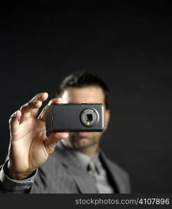 Businessman taking photos, mobile camera, black background