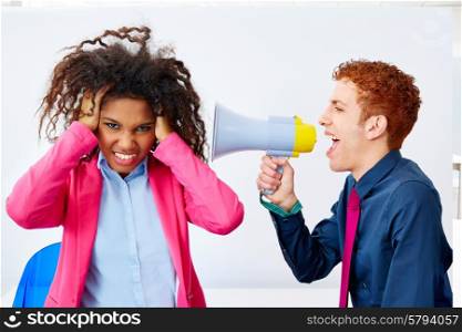 businessman talking in megaphone to african executive with scared expression