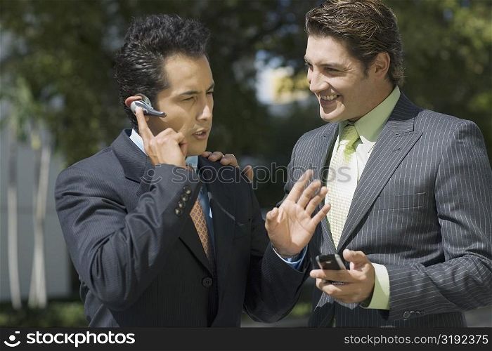 Businessman talking on a hands free device with another businessman standing beside him