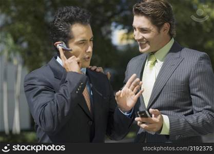 Businessman talking on a hands free device with another businessman standing beside him