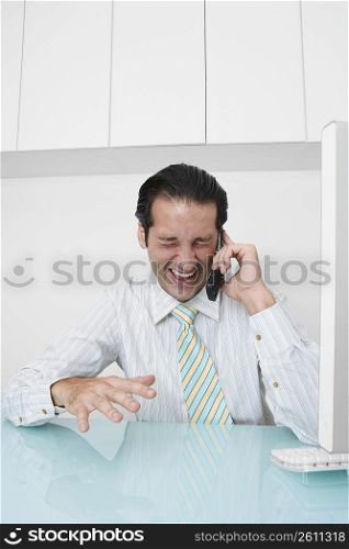 Businessman talking on a mobile phone and laughing in an office
