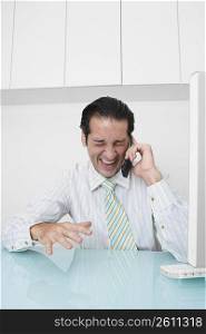 Businessman talking on a mobile phone and laughing in an office