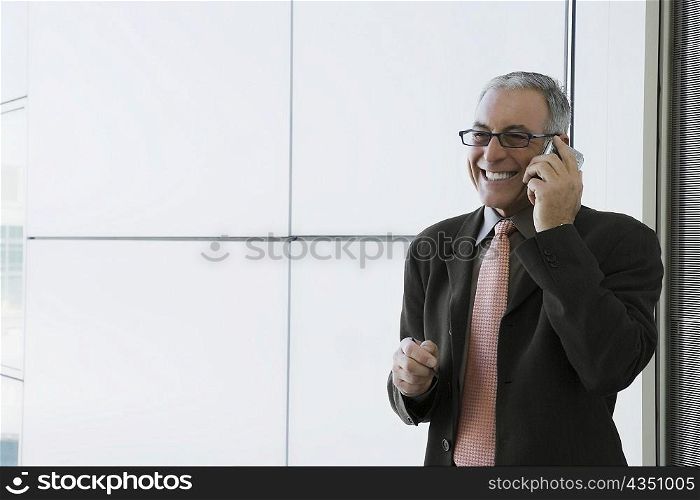 Businessman talking on a mobile phone and smiling in the waiting room of an airport
