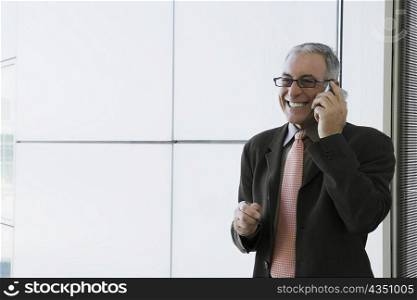 Businessman talking on a mobile phone and smiling in the waiting room of an airport