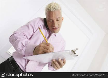 Businessman talking on a mobile phone and writing on a clipboard