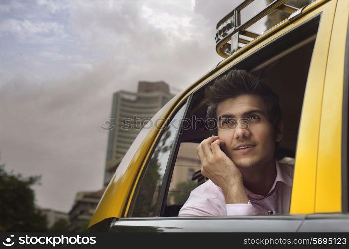 Businessman talking on a mobile phone in a taxi