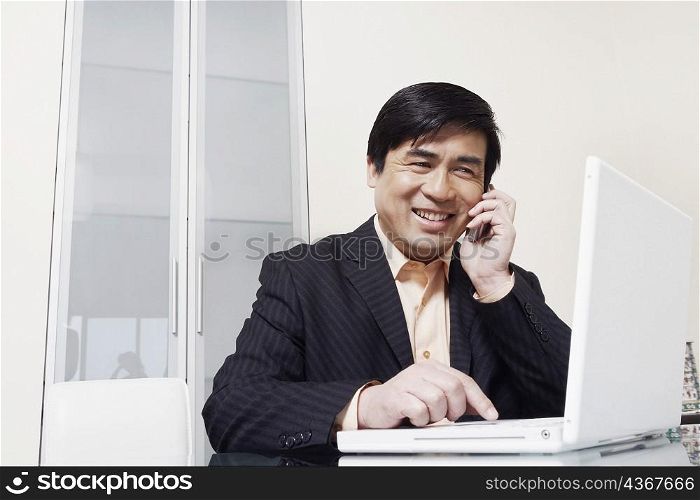 Businessman talking on a mobile phone using a laptop
