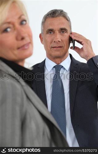 Businessman talking on his mobile phone beside his colleague