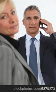 Businessman talking on his mobile phone beside his colleague