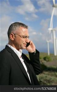 Businessman talking on his mobile phone in a wind turbine park