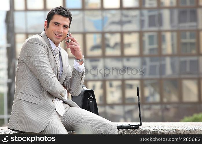 Businessman talking on phone in front of a laptop computer