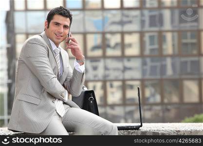 Businessman talking on phone in front of a laptop computer