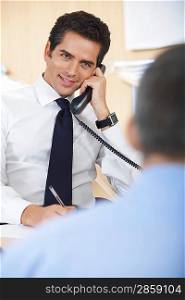 Businessman talking on phone in office silhouette of defocused man in foreground