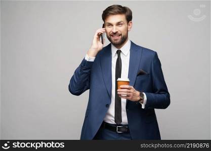 businessman talking on the phone and holding cup of coffee isolated over grey background in studio shooting. businessman talking on the phone and holding cup of coffee isolated over grey background