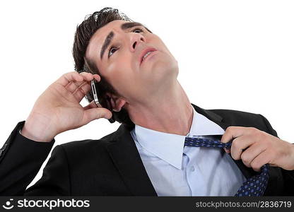 businessman talking on the phone and taking off his tie