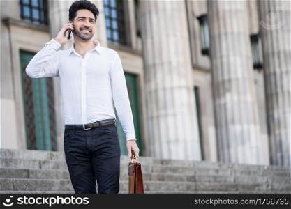 Businessman talking on the phone while standing on stairs outdoors. Business concept.