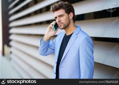 Businessman talking to his smartphone wearing blue suit outdoors.. Businessman talking to his smartphone wearing blue suit.