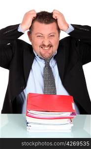 Businessman tearing his hair out over a pile of paperwork