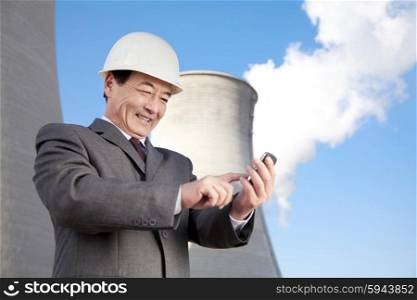 Businessman texting at power plant