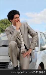 Businessman thinking by his car