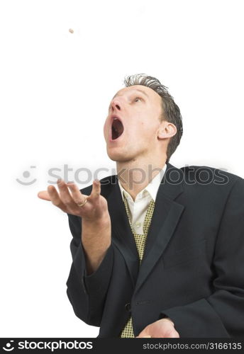 Businessman throwing a pill into the air and catching it open mouthed