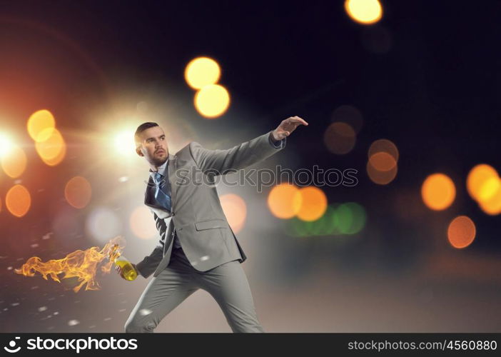 Businessman throwing petrol bomb. Aggressive businessman in suit throwing burning molotov cocktail