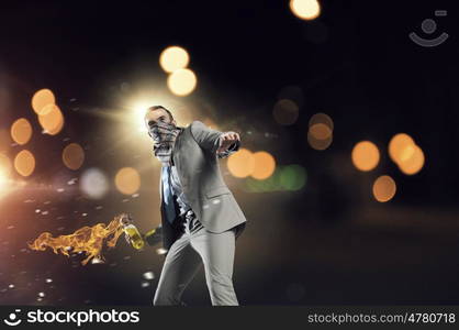 Businessman throwing petrol bomb. Aggressive businessman in suit throwing burning molotov cocktail