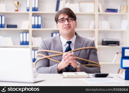 Businessman tied up with rope in office