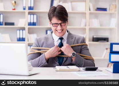 Businessman tied up with rope in office