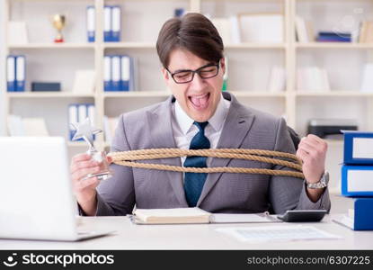 Businessman tied up with rope in office