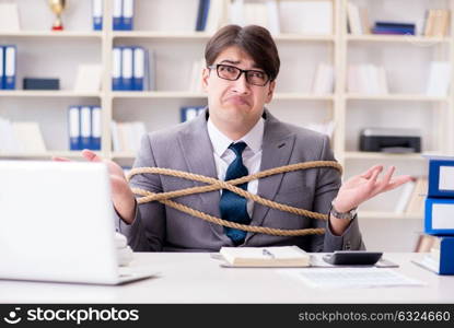 Businessman tied up with rope in office