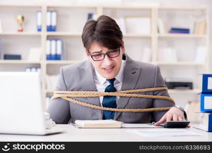 Businessman tied up with rope in office