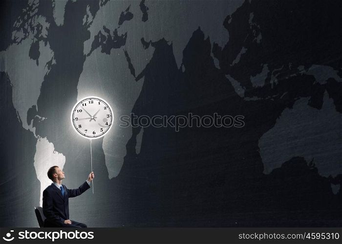 Businessman tries to change time. Businessman with clock balloon on dark background