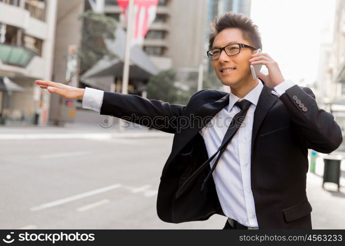 Businessman trying to catch a taxi in business cuty district. Waving for a taxi in city