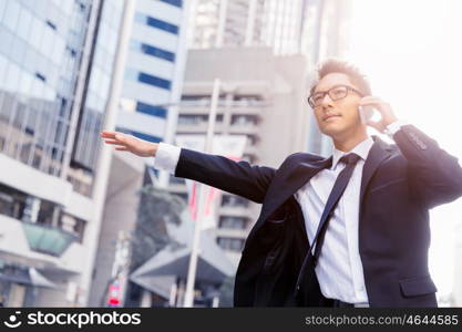 Businessman trying to catch a taxi in business cuty district. Waving for a taxi in city