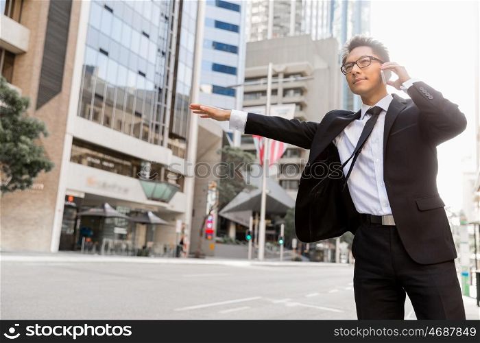 Businessman trying to catch a taxi in business cuty district. Waving for a taxi in city