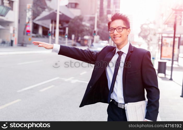 Businessman trying to catch a taxi in business cuty district. Waving for a taxi in city