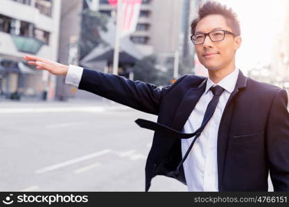 Businessman trying to catch a taxi in business cuty district. Waving for a taxi in city