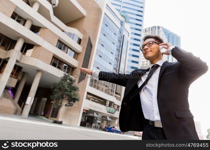 Businessman trying to catch a taxi in business cuty district. Waving for a taxi in city