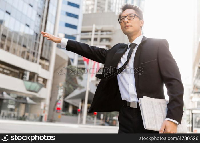 Businessman trying to catch a taxi in business cuty district. Waving for a taxi in city