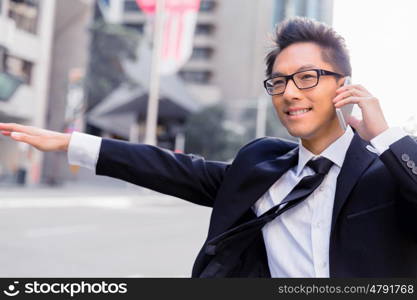 Businessman trying to catch a taxi in business cuty district. Waving for a taxi in city