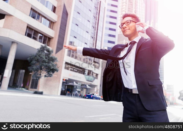 Businessman trying to catch a taxi in business cuty district. Waving for a taxi in city