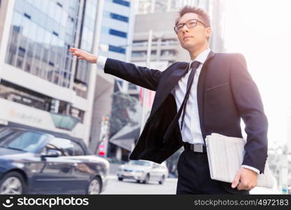 Businessman trying to catch a taxi in business cuty district. Waving for a taxi in city