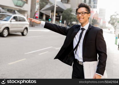 Businessman trying to catch a taxi in business cuty district. Waving for a taxi in city