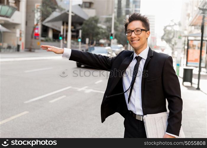 Businessman trying to catch a taxi in business cuty district. Waving for a taxi in city