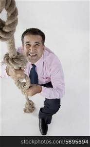 Businessman trying to climb a rope