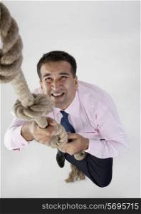 Businessman trying to climb a rope
