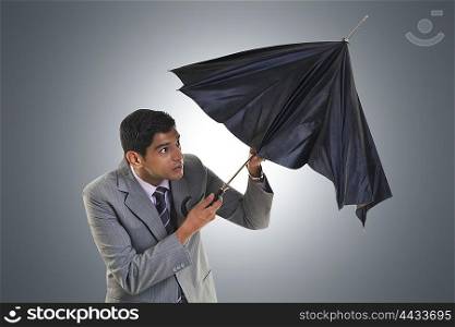Businessman trying to open umbrella